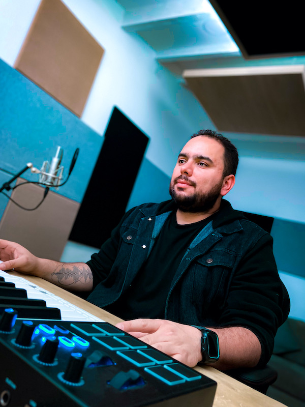 A person sitting at a mixing desk in a sound studio, looking up contemplatively. A person sitting at a mixing desk in a sound studio, looking up contemplatively.